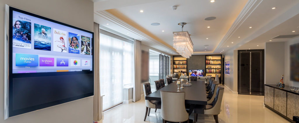 Dining room with lighting and a smart control panel on the wall.